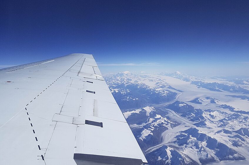 Above the Alaskan mountains and glaciers.